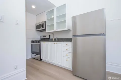 a kitchen with white cabinets and refrigerator