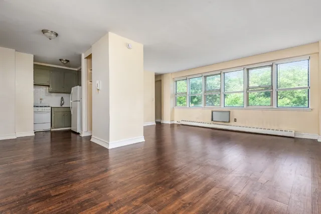 a view of empty room with wooden floor and a window