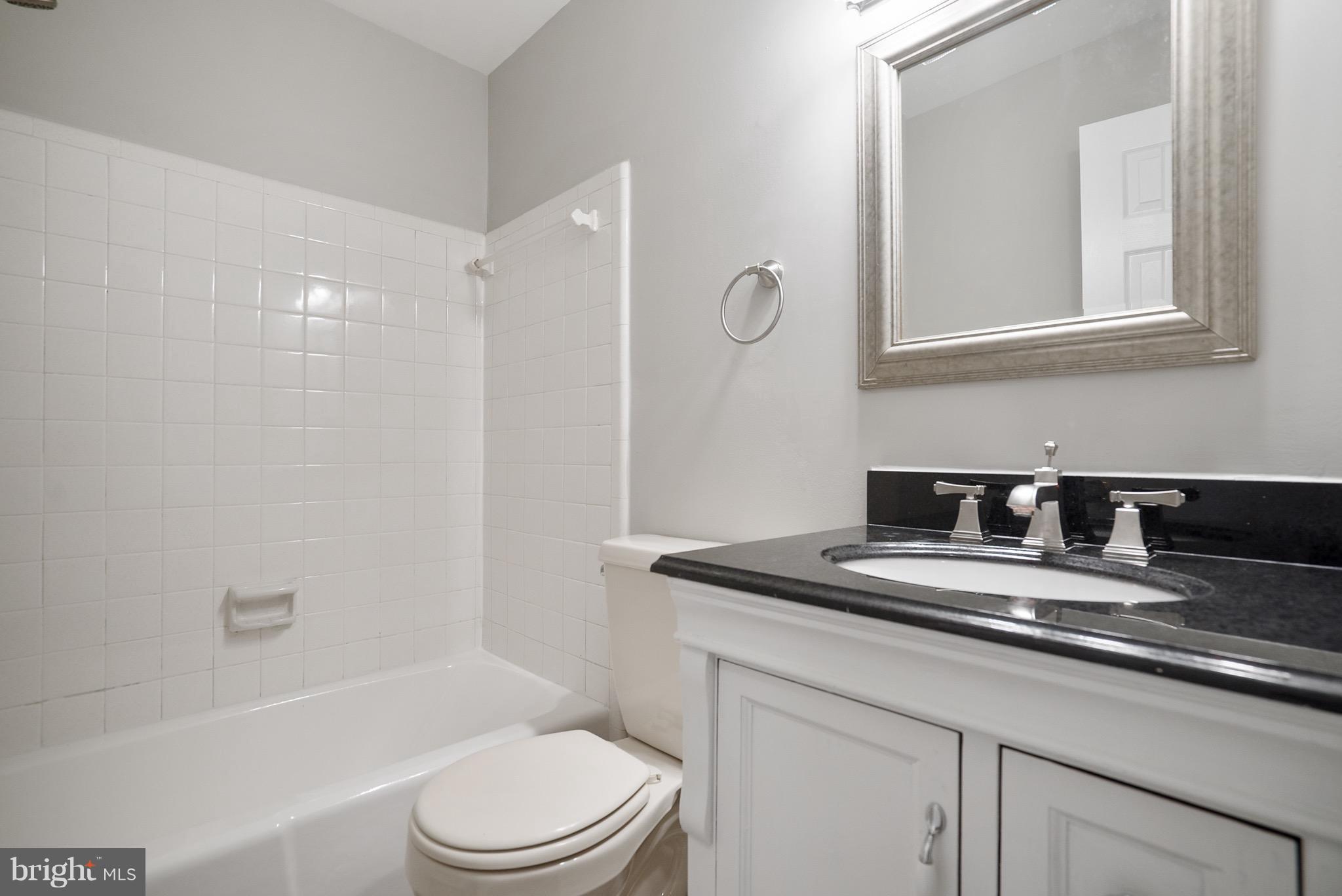 6928 Sydenstricker Road Springfield, VA 22153 - Photo 16 of 30 a bathroom with a granite countertop sink a toilet a mirror and shower