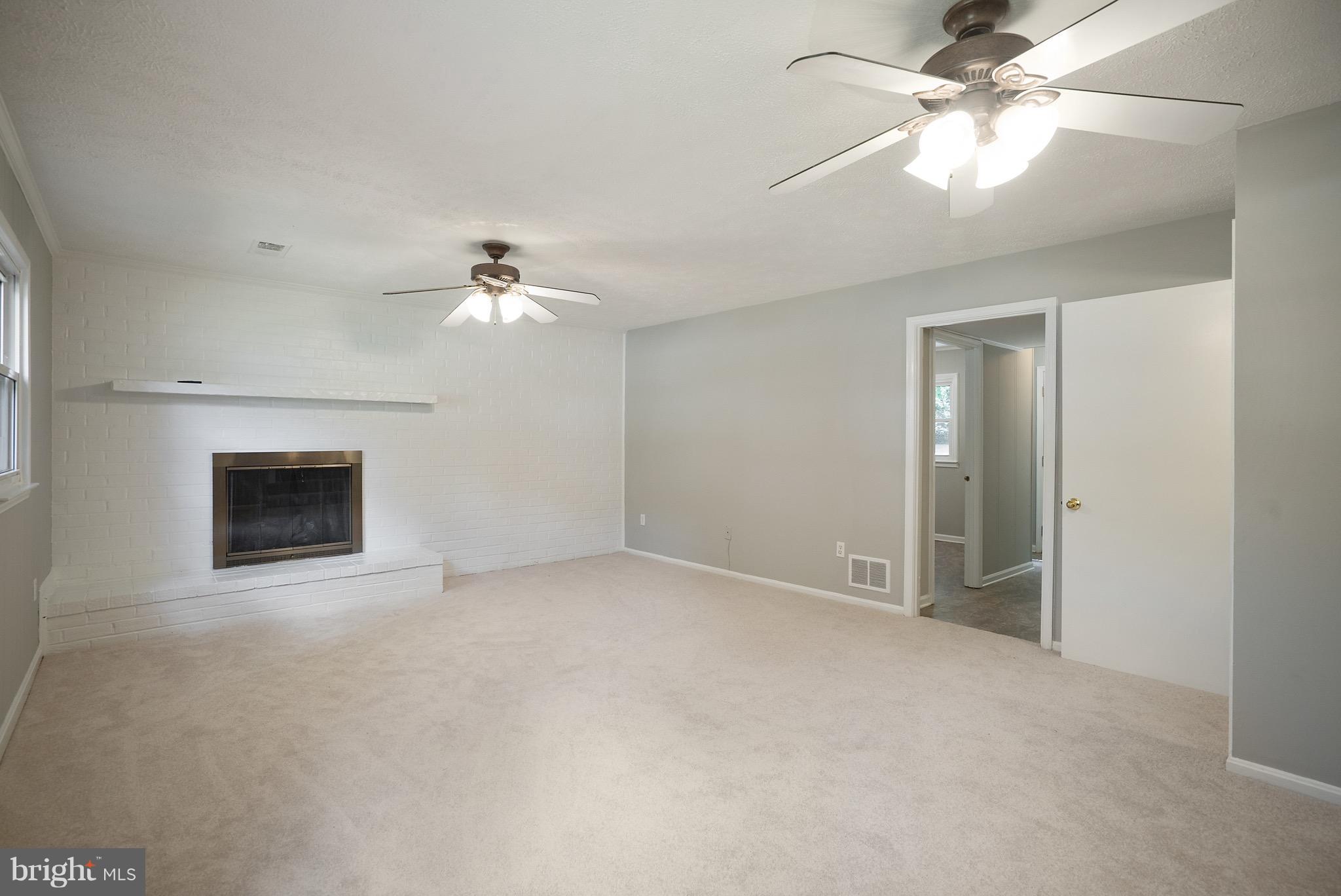 6928 Sydenstricker Road Springfield, VA 22153 - Photo 21 of 30 an empty room with a ceiling fan and a fireplace