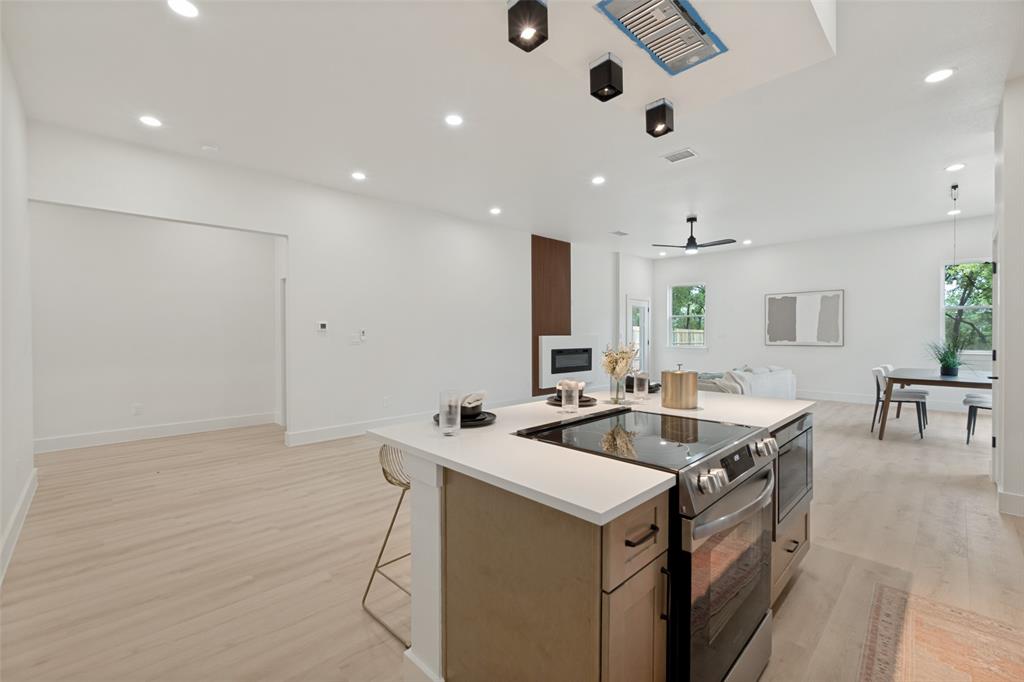 1143 Riverwood Road Dallas, TX 75217 - Photo 12 of 24 Expansive kitchen island with a built-in electric range and stainless steel oven, complemented by light wood-finish flooring