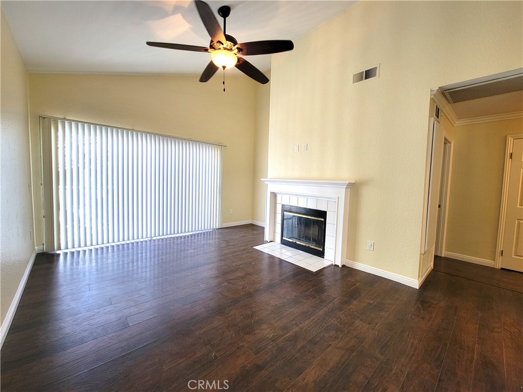 an empty room with wooden floor fireplace and fan
