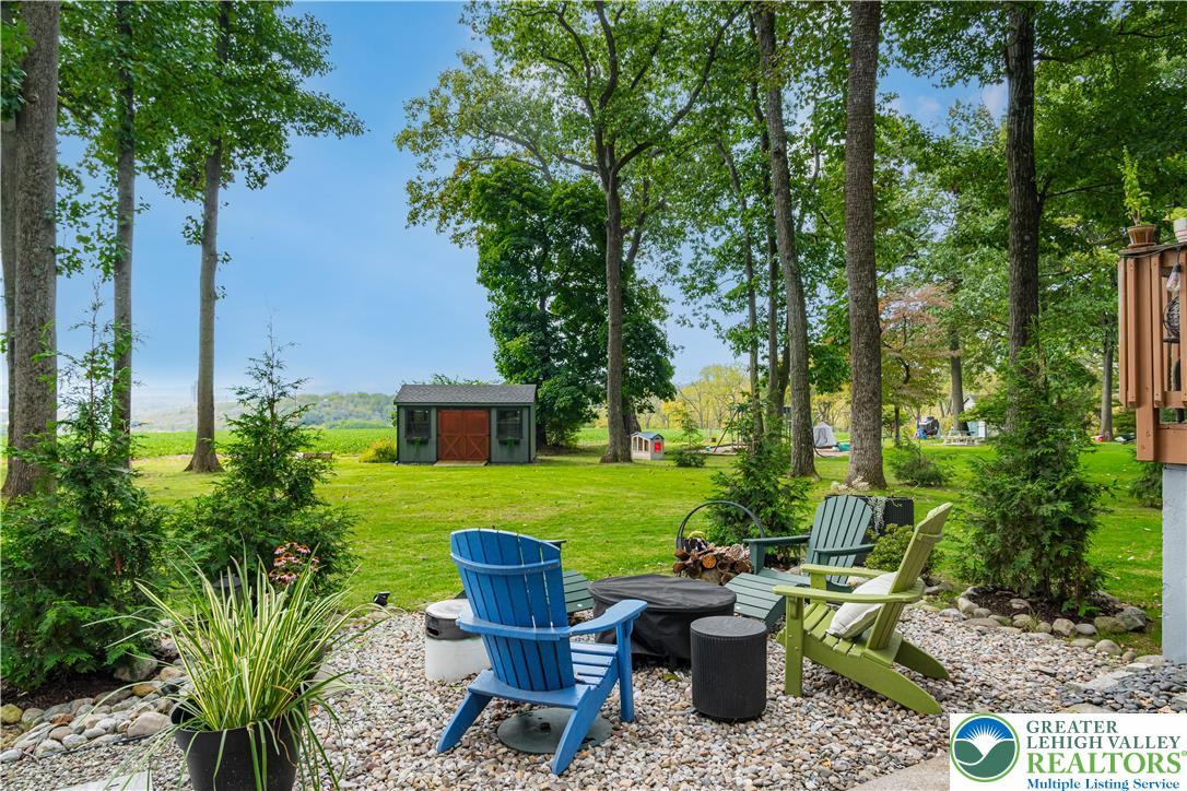 2569 Woods Edge Road Bath, PA 18014 - Photo 32 of 40 Towering trees shade a gravel seating patio overlooking a wide-open lawn with a detached shed.
