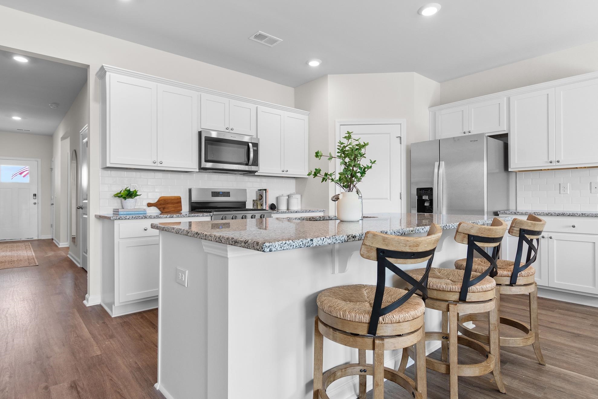 620 Anthem Court Conway, SC 29527 - Photo 9 of 25 Kitchen with tasteful backsplash, a kitchen island with sink, light stone countertops, white cabinetry, and recessed lighting