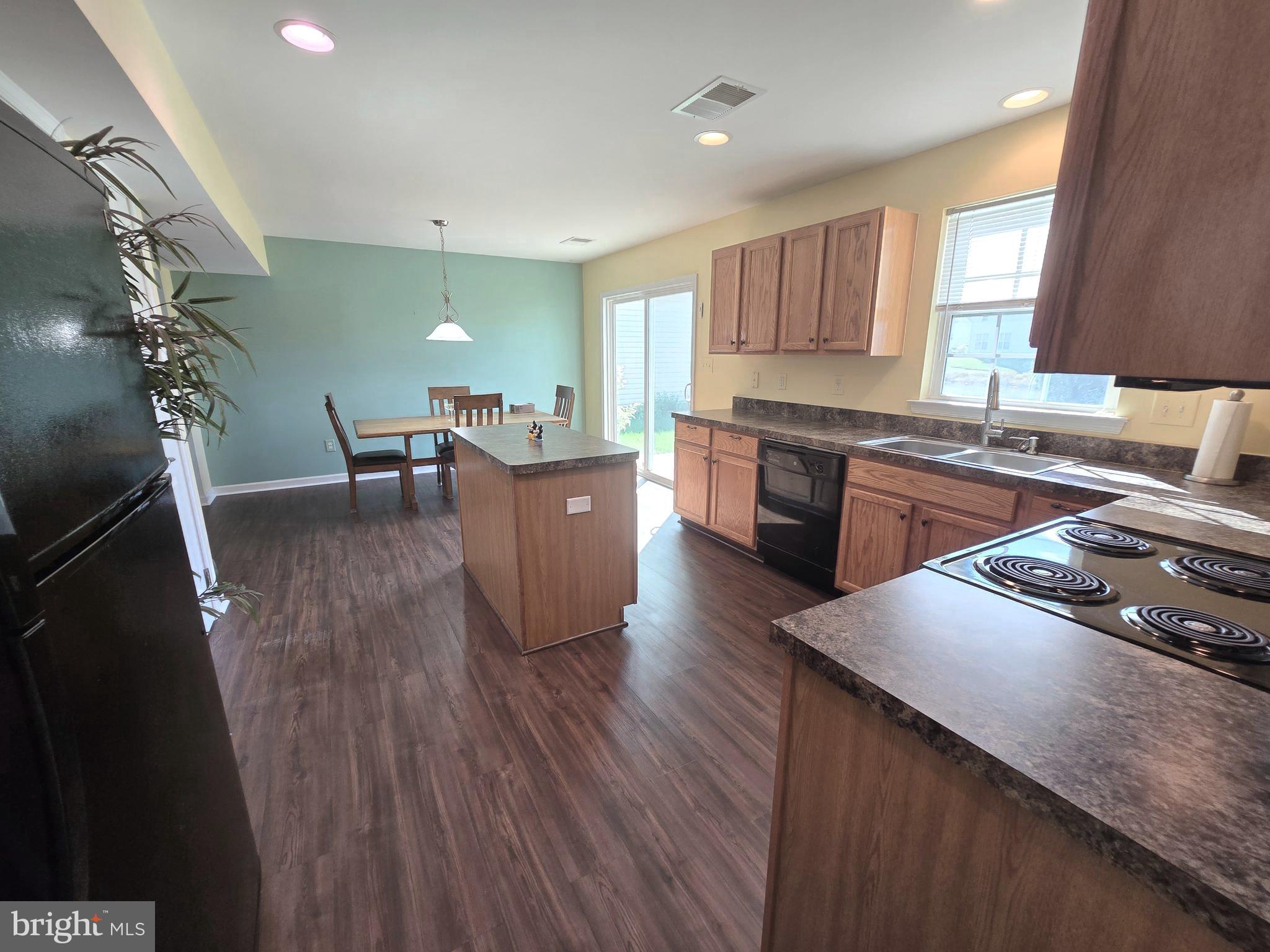 181 Bobbys Branch Road, Unit 35 Millsboro, DE 19966 - Photo 11 of 26 a kitchen with stainless steel appliances granite countertop wooden floors sink stove dining table and chairs