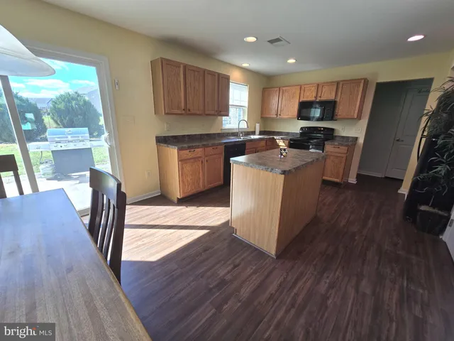 a kitchen with a sink a stove a refrigerator cabinets and wooden floor