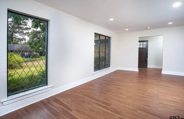 a view of an empty room with wooden floor and a window