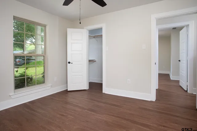 a view of empty room with wooden floor and fan