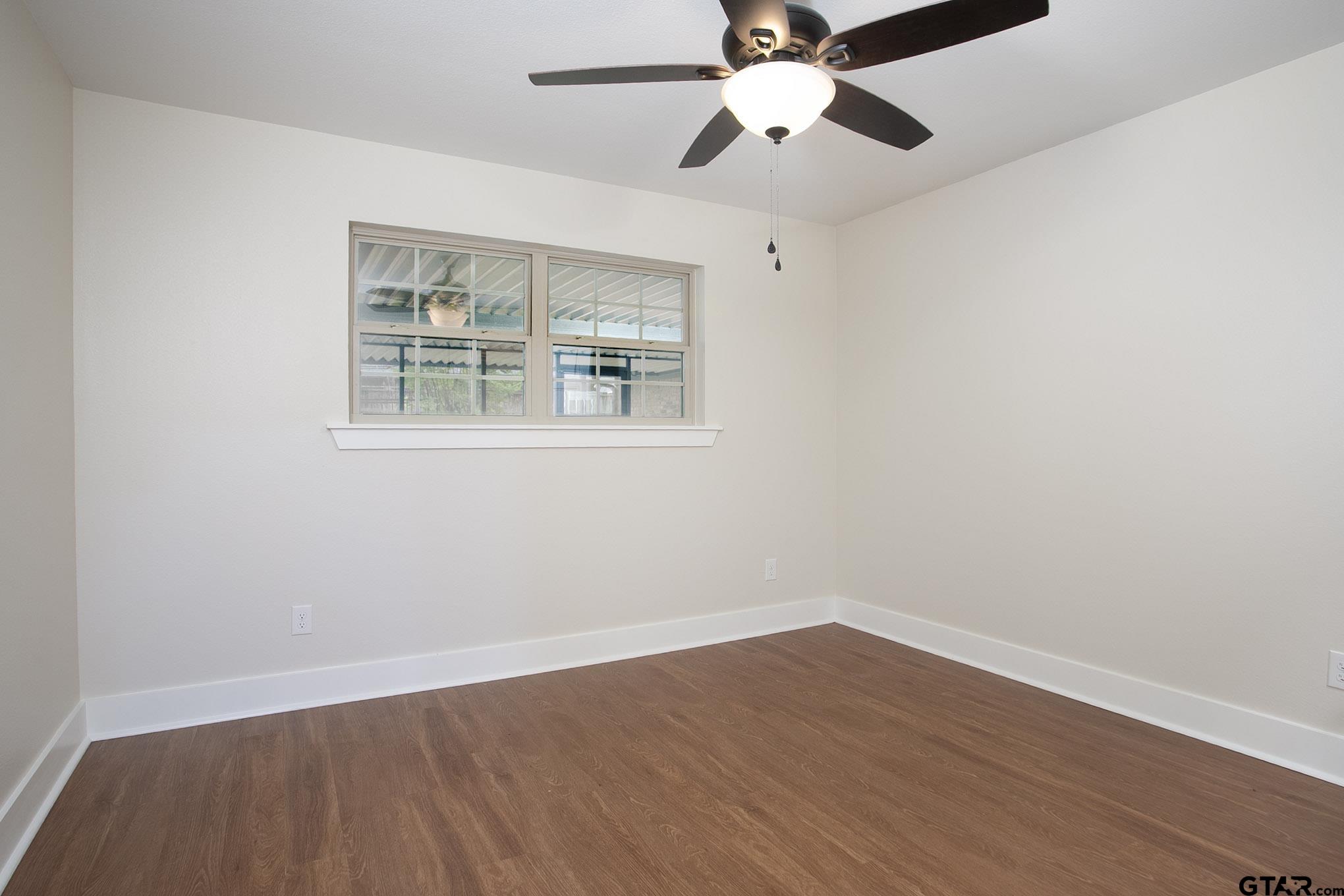 610 Rockwall Drive Longview, TX 75604 - Photo 18 of 39 an empty room with wooden floor fan and windows