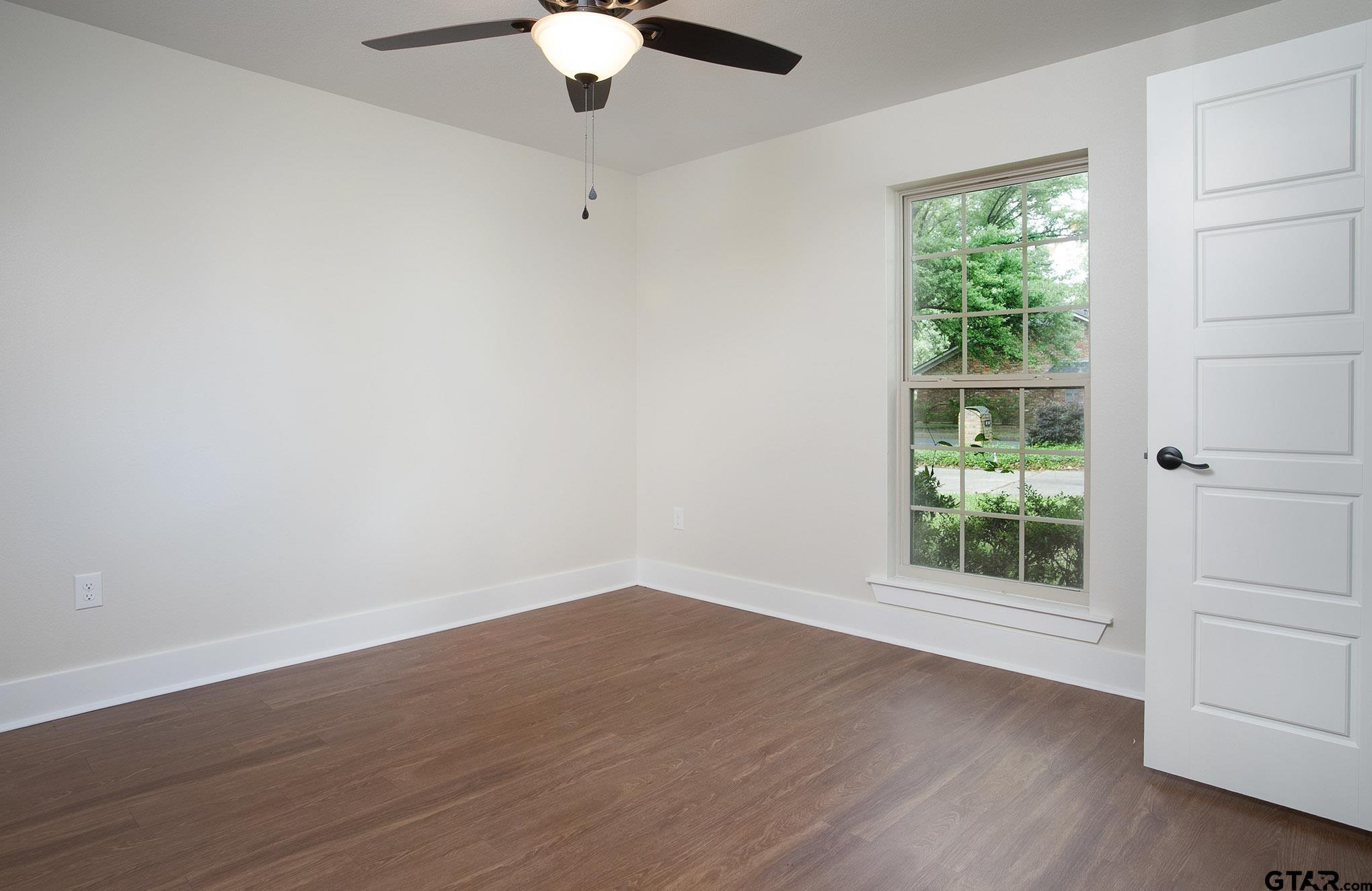 610 Rockwall Drive Longview, TX 75604 - Photo 23 of 39 an empty room with wooden floor chandelier fan and windows