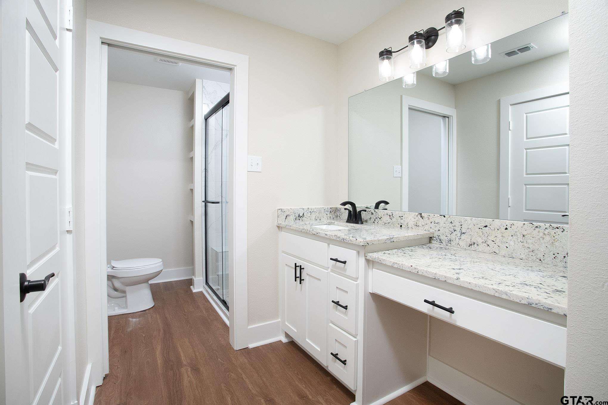 610 Rockwall Drive Longview, TX 75604 - Photo 24 of 39 a bathroom with a granite countertop sink a toilet and a mirror