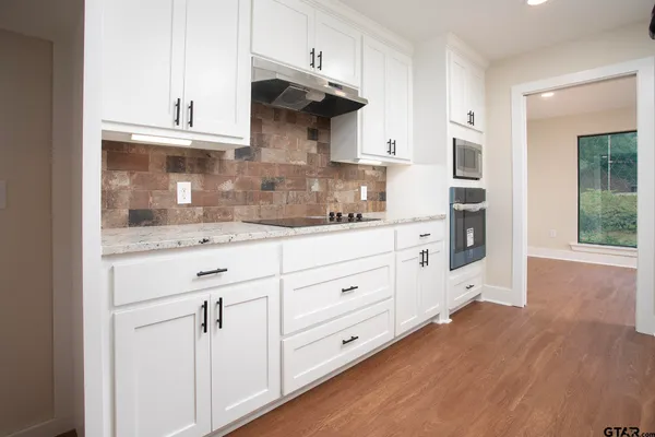a kitchen with stainless steel appliances white cabinets and a wooden floors