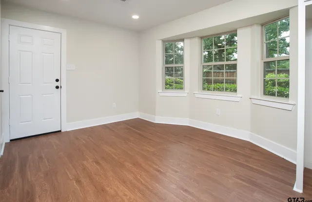 a view of an empty room with wooden floor and a window