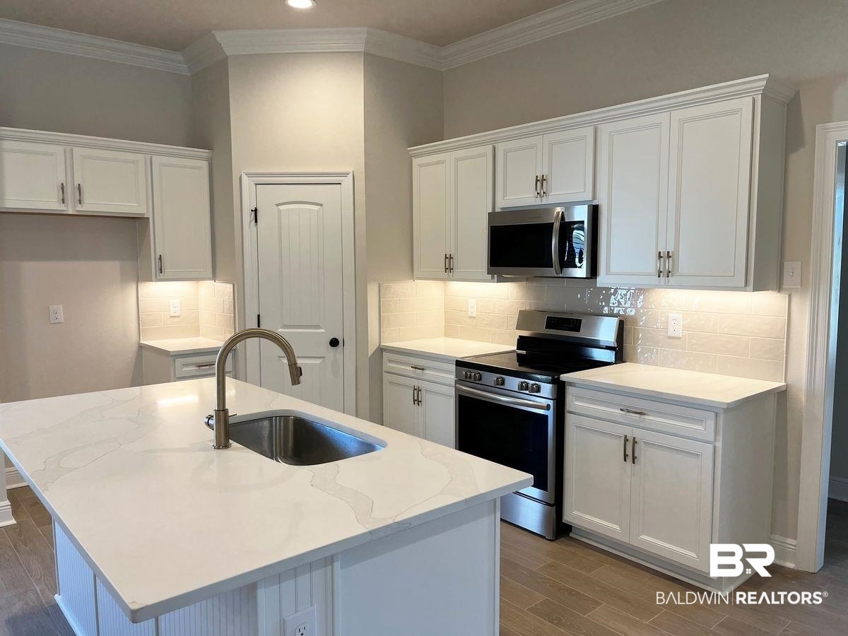 1733 Breckinridge Place Foley, AL 36535 - Photo 2 of 18 Kitchen featuring appliances with stainless steel finishes, an island with sink, white cabinets, light wood-type flooring, and sink