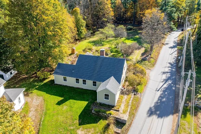 an aerial view of a house with swimming pool and large trees