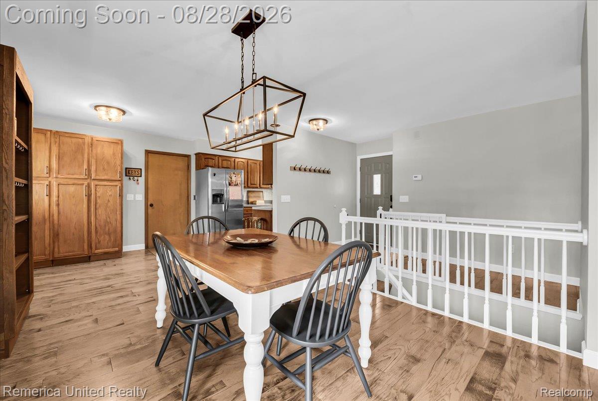 3687 Van Amberg Road Brighton, MI 48114 - Photo 15 of 56 Wood-finish flooring, white spindle railing, and a geometric chandelier
