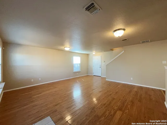 an empty room with wooden floor and windows