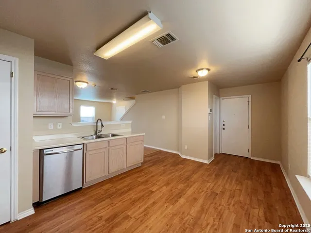 a kitchen with white cabinets and wooden floor