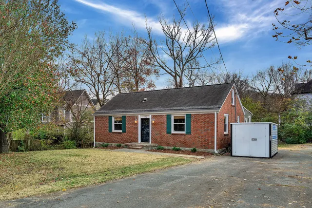 a view of a house with a yard and large tree