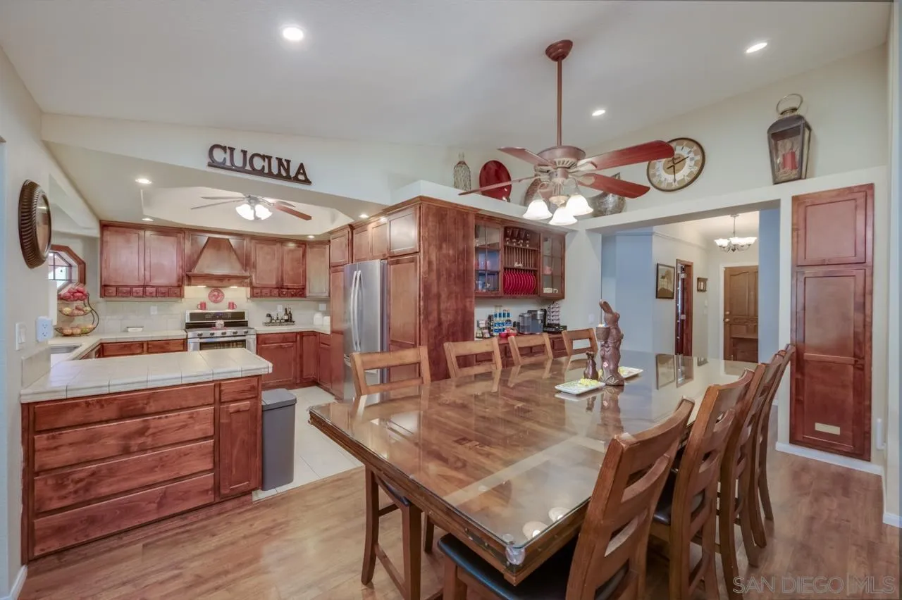 13499 Khuram Street Lakeside, CA 92040 - Photo 13 of 50 a dining room with wooden floor a chandelier a wooden table and chairs