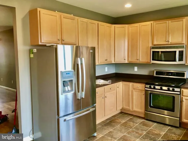 a kitchen with stainless steel appliances granite countertop a refrigerator stove and cabinets