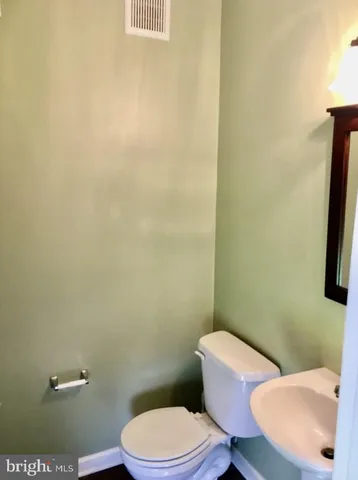 a white toilet sitting next to a white sink and vanity