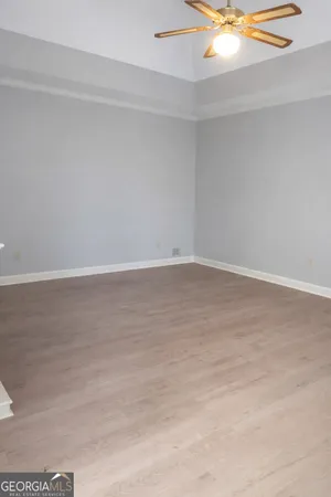 a view of an empty room with a fireplace and chandelier fan