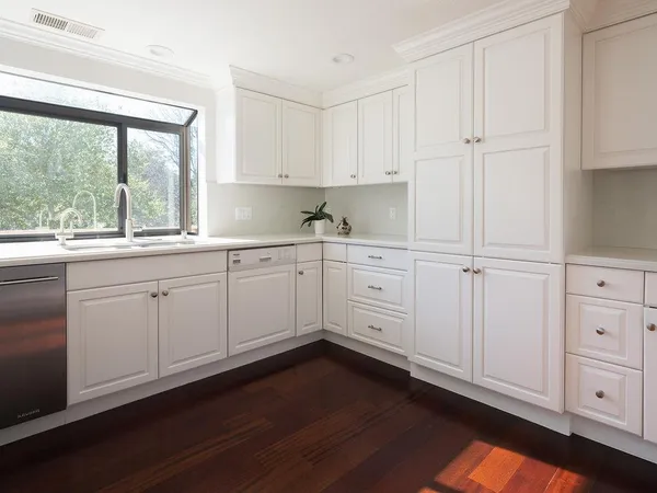 a kitchen with white cabinets and a window