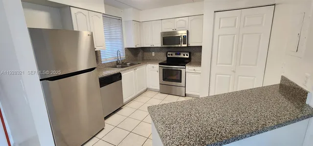 a kitchen with stainless steel appliances granite countertop a refrigerator and a sink