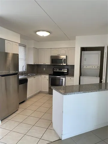 a kitchen with stainless steel appliances granite countertop a refrigerator a stove a sink a microwave and white cabinets