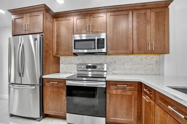a kitchen with granite countertop a refrigerator stove and microwave