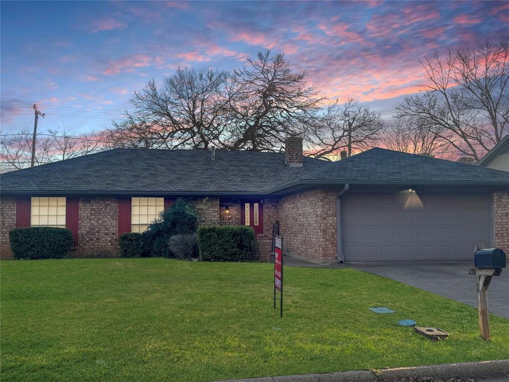 a brick house with a yard plants and large trees