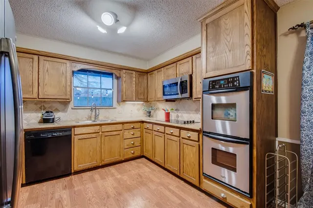 a kitchen with stainless steel appliances granite countertop a refrigerator a stove top oven a sink dishwasher and wooden cabinets