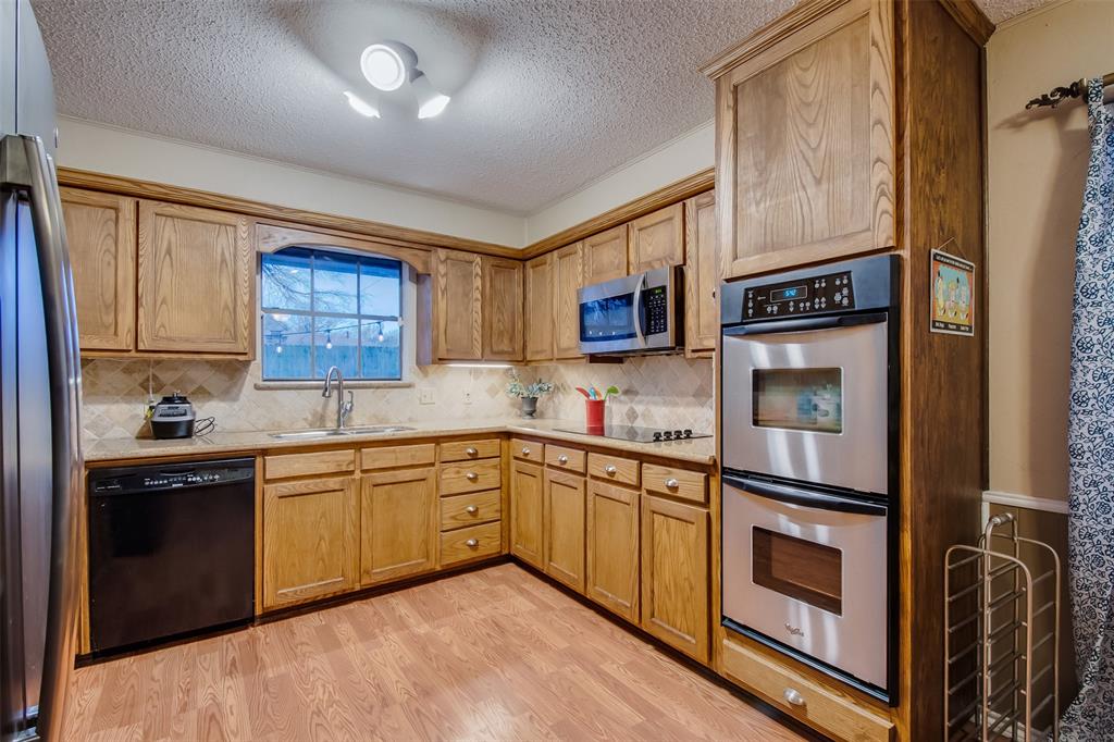 5718 Sagebrush Trail Arlington, TX 76017 - Photo 8 of 26 a kitchen with stainless steel appliances granite countertop a refrigerator a stove top oven a sink dishwasher and wooden cabinets