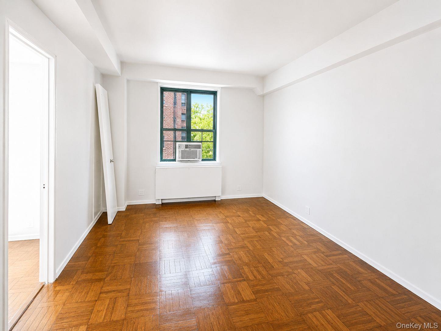 1558 Unionport Road, Unit 2D Bronx, NY 10462 - Photo 3 of 9 an empty room with wooden floor and windows