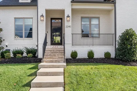 a view of a hallway with wooden floor and a bathroom