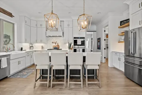 a kitchen with stainless steel appliances a dining table chairs refrigerator and sink