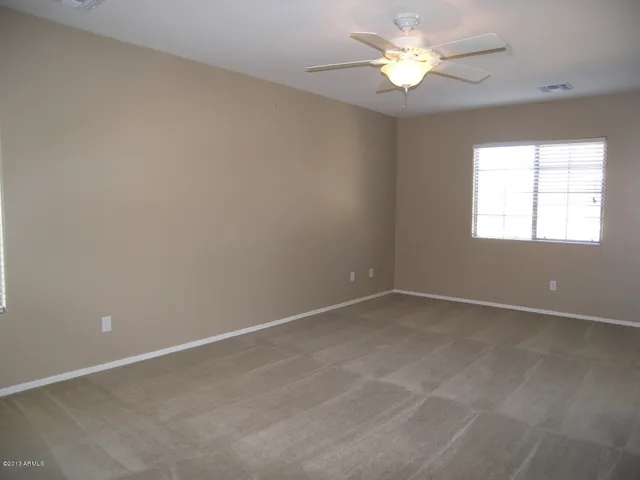 an empty room with a window and a fan
