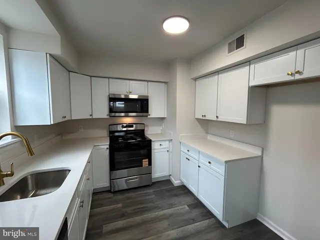 a kitchen with granite countertop white cabinets and stainless steel appliances