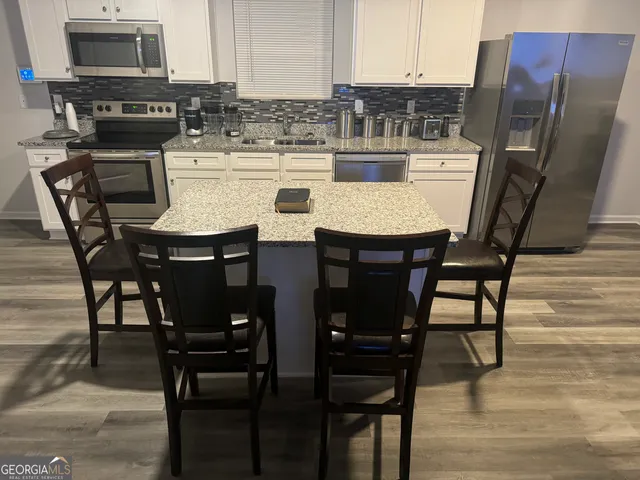 a kitchen with stainless steel appliances kitchen island granite countertop a table chairs stove and refrigerator