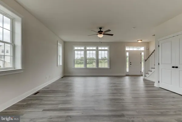 a view of an empty room with wooden floor and a ceiling fan