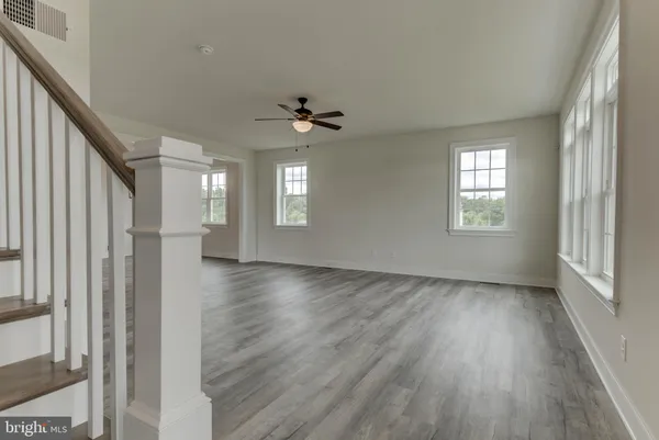 a view of an empty room with window and wooden floor