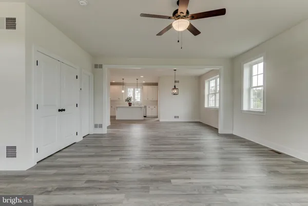 a view of an empty room with wooden floor and fan