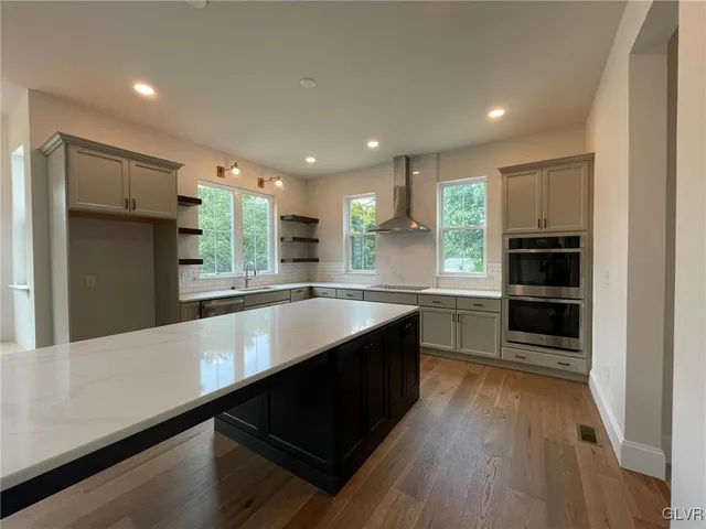 a large kitchen with stainless steel appliances a large counter top stove and cabinets