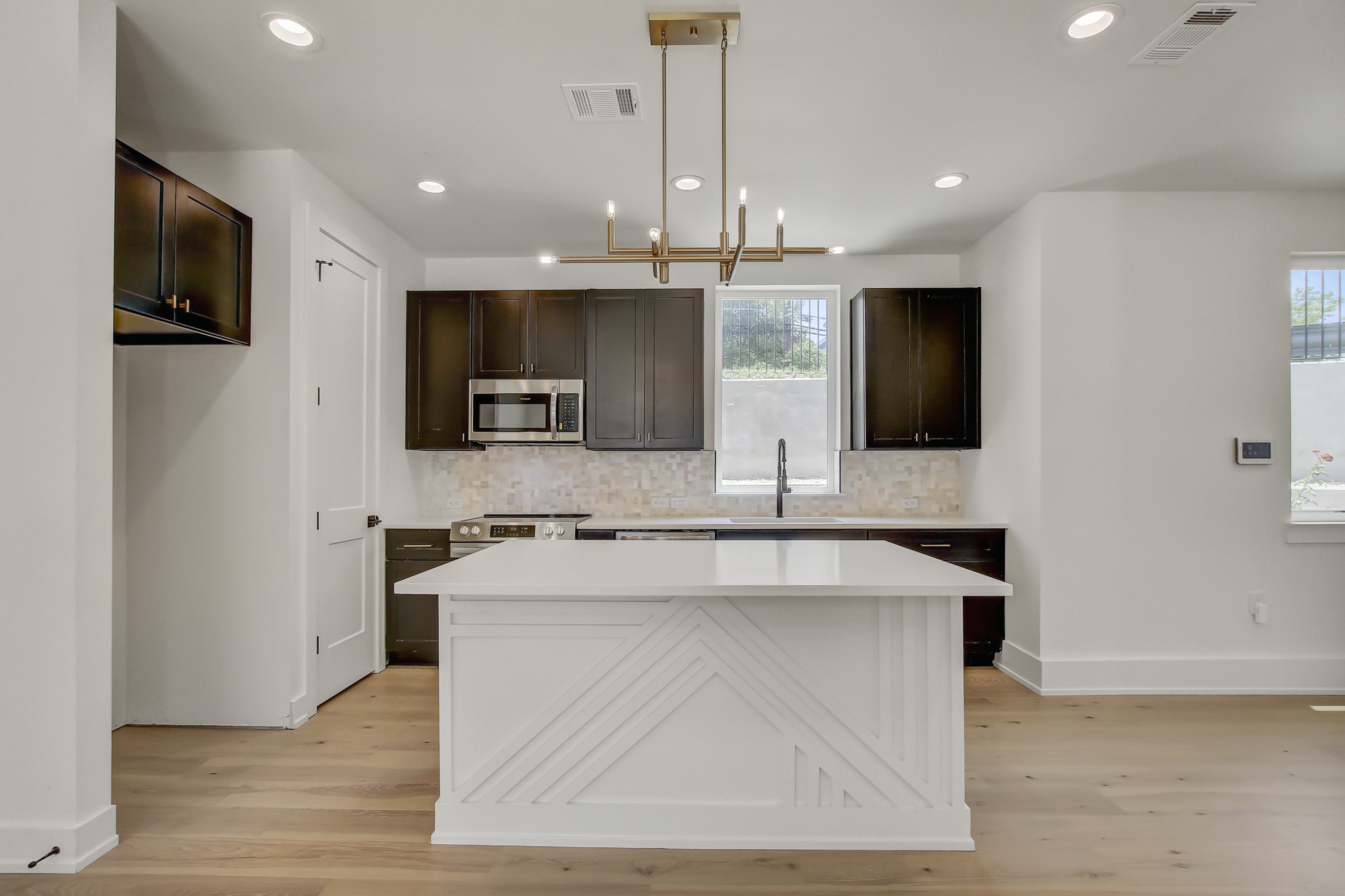 4127 East 12th Street, Unit 8 Austin, TX 78721 - Photo 11 of 32 a large kitchen with stainless steel appliances kitchen island granite countertop a sink and a stove top oven with wooden floor