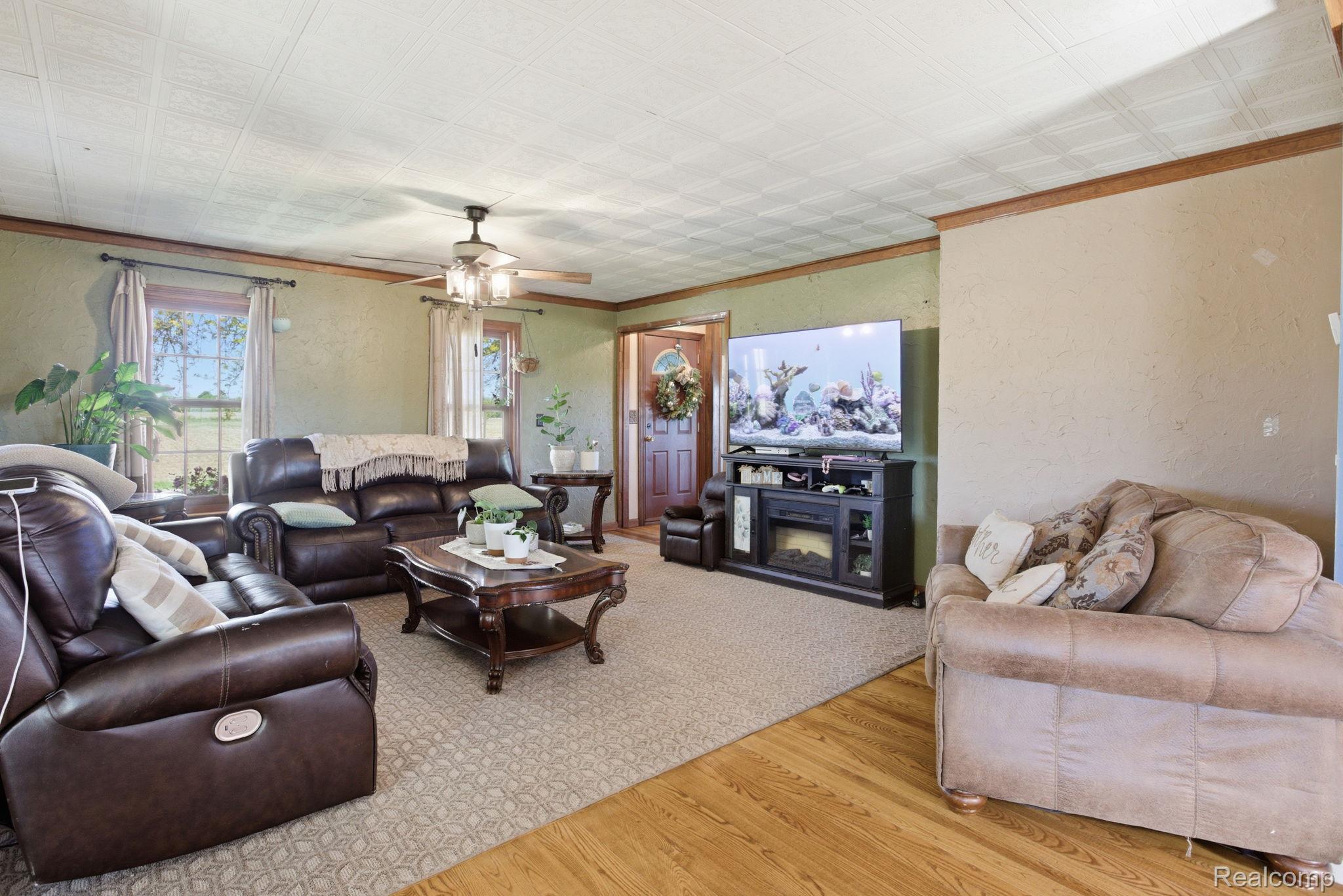 14104 Carleton West Road Carleton, MI 48117 - Photo 10 of 58 Living room with an ornate ceiling, wood finished floors, a textured wall, a ceiling fan, and ornamental molding