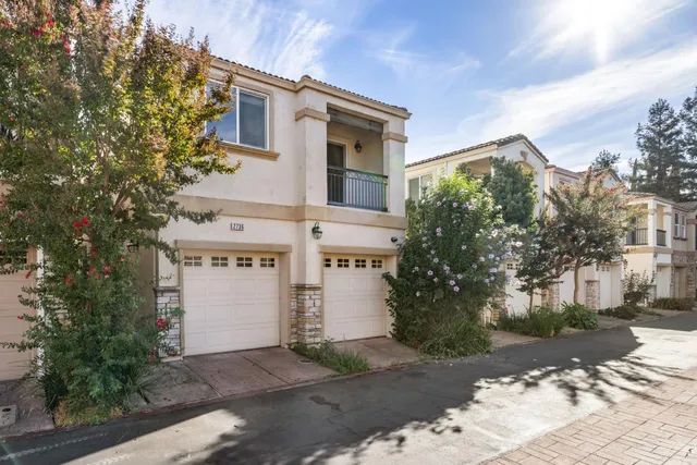a view of a white house with a large tree
