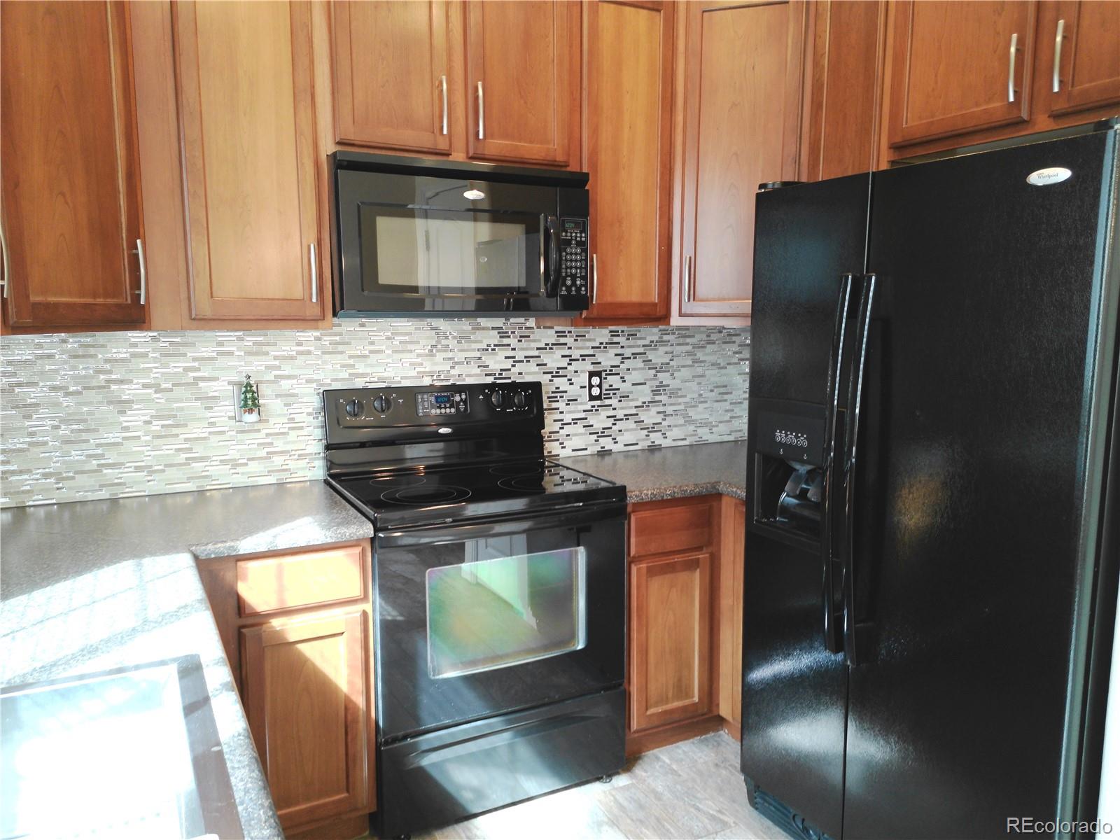 4714 ROWLAND Heights Colorado Springs, CO 80923 - Photo 15 of 41 a kitchen with granite countertop a refrigerator stove and microwave