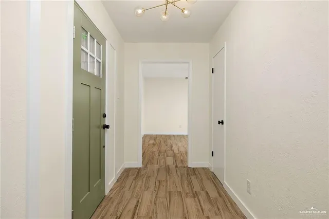 a view of a hallway with wooden floor and a bathroom