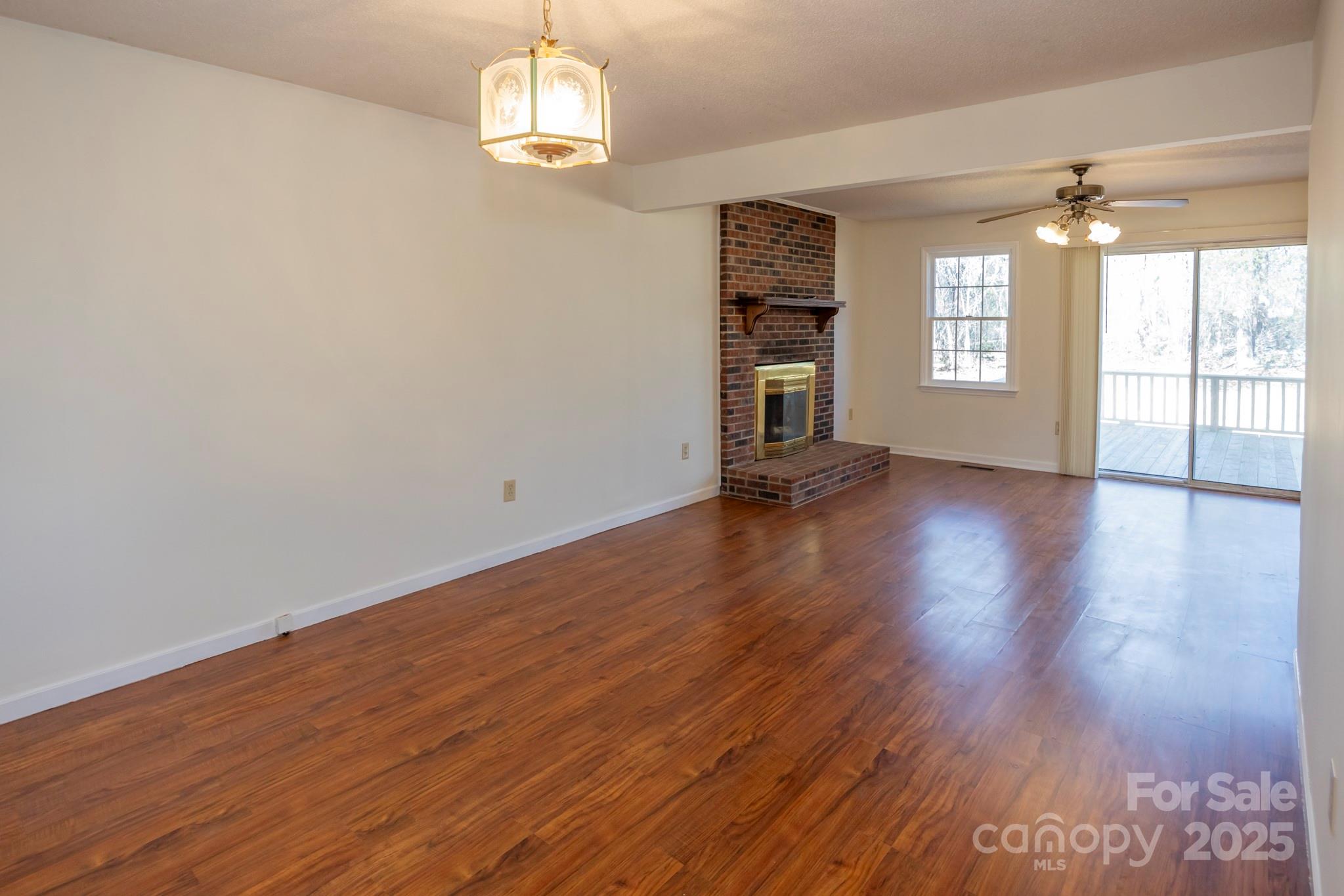 395 Thompson Road Rutherfordton, NC 28139 - Photo 8 of 25 an empty room with wooden floor chandelier and windows